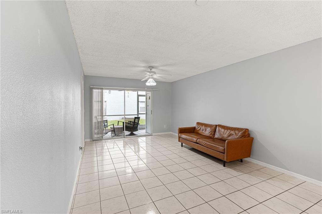 161 Wading Bird Circle, Unit L101 Naples, FL 34110 - Photo 13 of 44 Living area with a textured ceiling, light tile patterned floors, and a ceiling fan