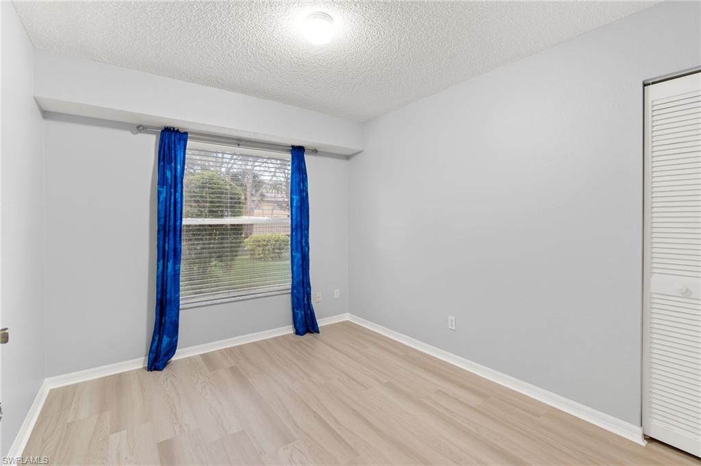 161 Wading Bird Circle, Unit L101 Naples, FL 34110 - Photo 17 of 35 a view of an empty room with wooden floor and a window