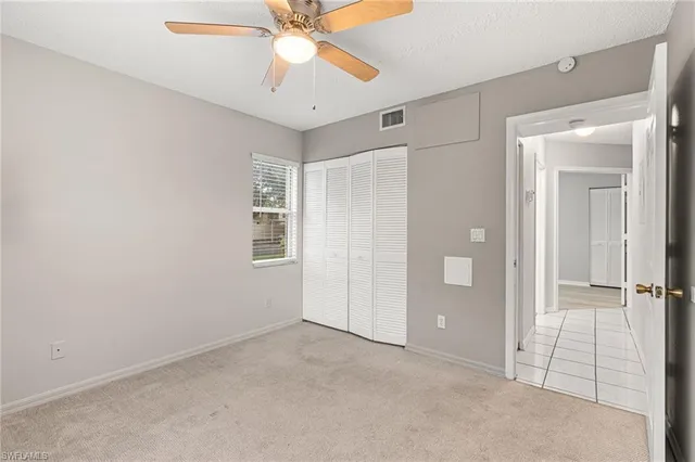 an empty room with a window and a ceiling fan