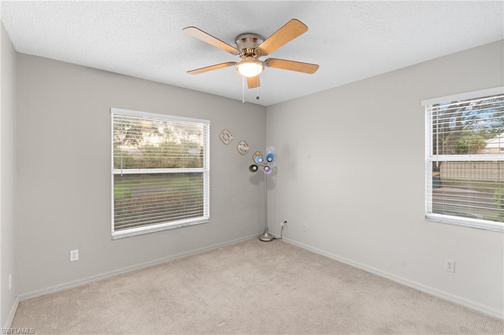 161 Wading Bird Circle, Unit L101 Naples, FL 34110 - Photo 27 of 44 Unfurnished room with light colored carpet, a textured ceiling, plenty of natural light, and ceiling fan