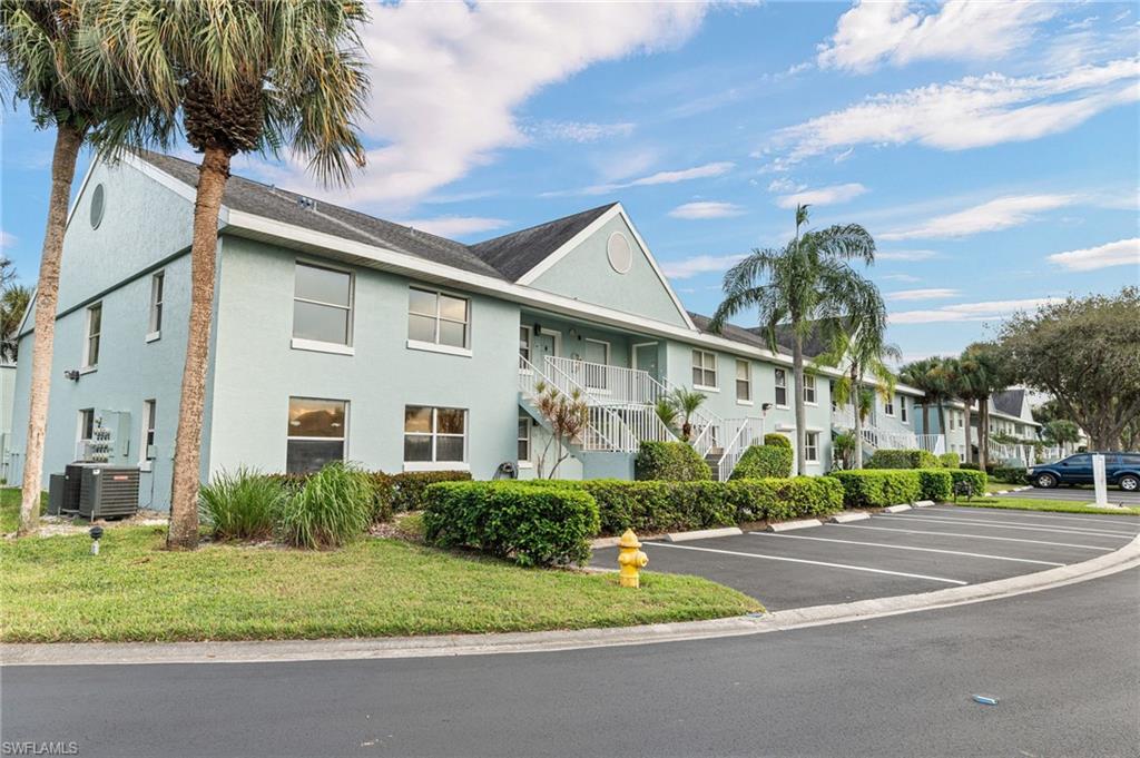 161 Wading Bird Circle, Unit L101 Naples, FL 34110 - Photo 33 of 44 View of front of property with stairway, stucco siding, uncovered parking, and roof with shingles