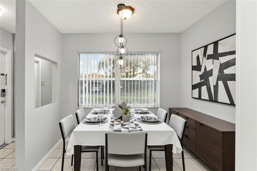 161 Wading Bird Circle, Unit L101 Naples, FL 34110 - Photo 4 of 44 Dining area virtual staged featuring a textured ceiling, plenty of natural light, hanging lights, and light tile patterned flooring