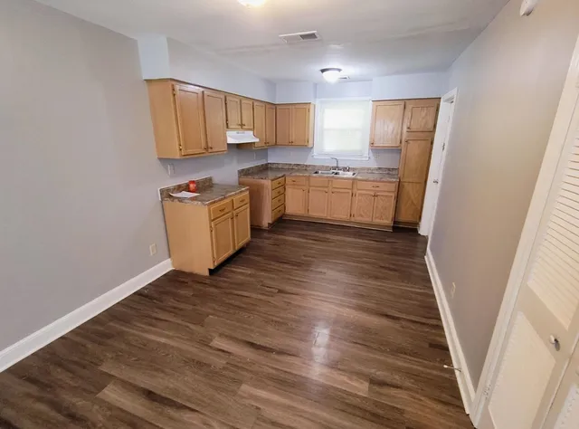 a kitchen with granite countertop a sink cabinets and wooden floor