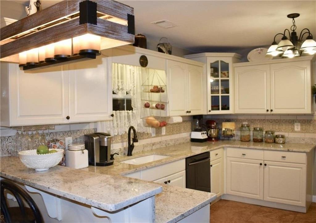 1599 Lower River Road Covington, GA 30016 - Photo 2 of 23 a kitchen with a sink dishwasher a stove a microwave oven and white cabinets