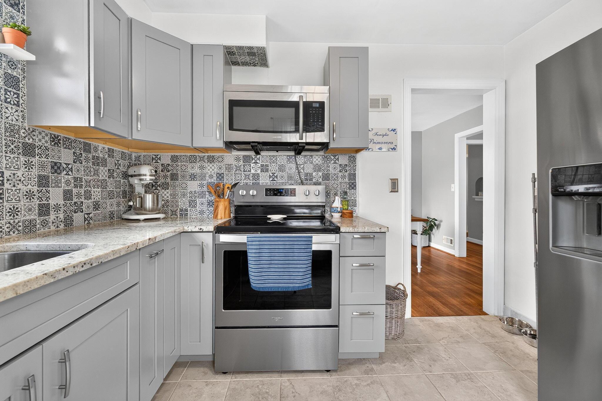 492 Wetmore Road Columbus, OH 43214 - Photo 20 of 55 Kitchen featuring stainless steel appliances, patterned tile backsplash, light-toned cabinetry with coordinating countertops, and tile flooring