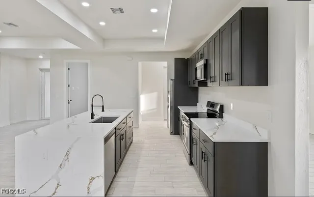 a kitchen with stainless steel appliances a sink dishwasher a stove and a refrigerator