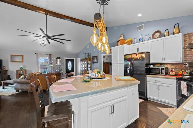 a kitchen with stainless steel appliances kitchen island granite countertop a table chairs in it and a sink