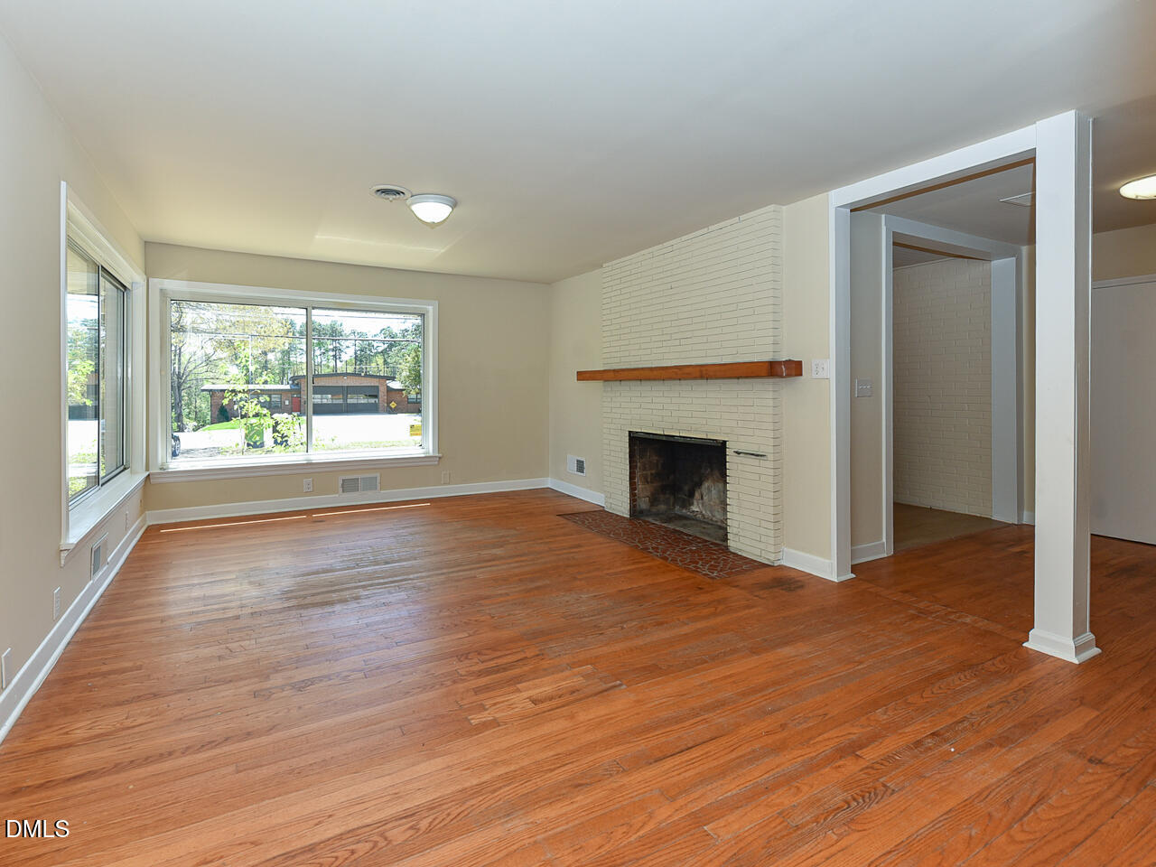 4916 Western Boulevard Raleigh, NC 27606 - Photo 8 of 18 an empty room with wooden floor fireplace and windows