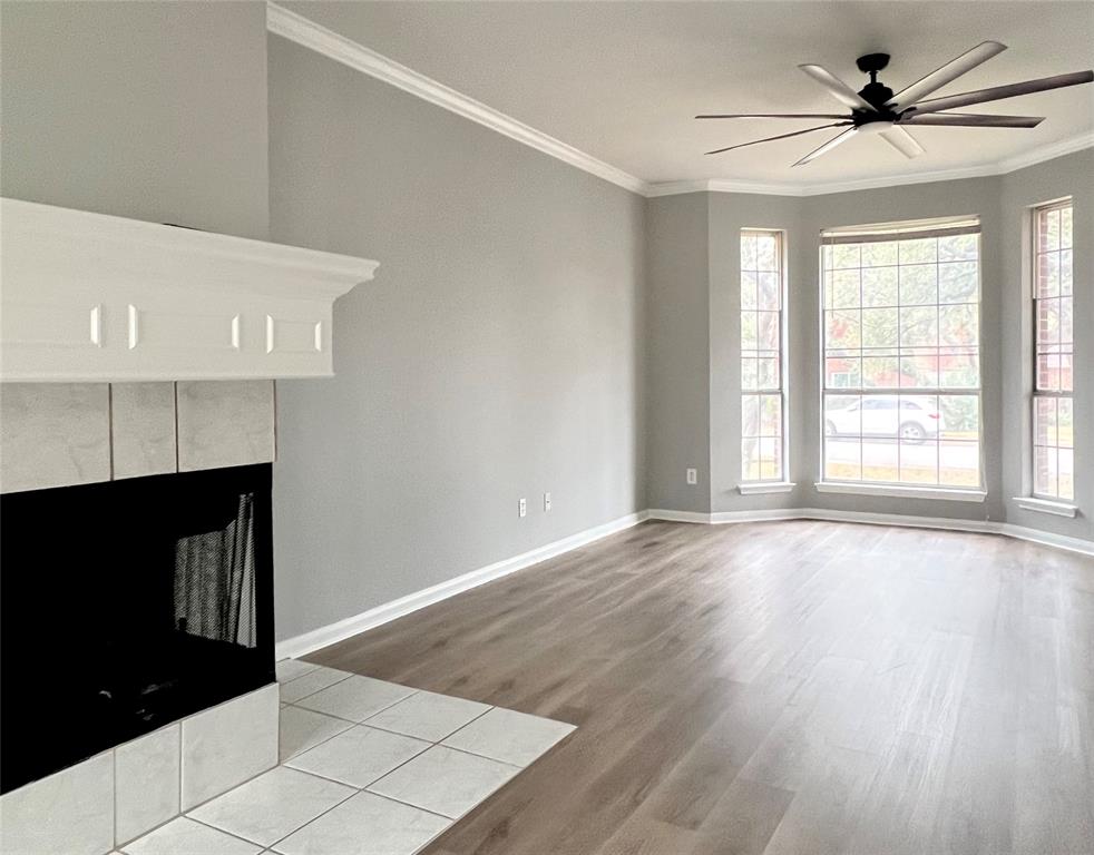 1809 Springwater Drive Round Rock, TX 78681 - Photo 1 of 25 Unfurnished living room with crown molding, a tiled fireplace, a ceiling fan, and light wood-style floors