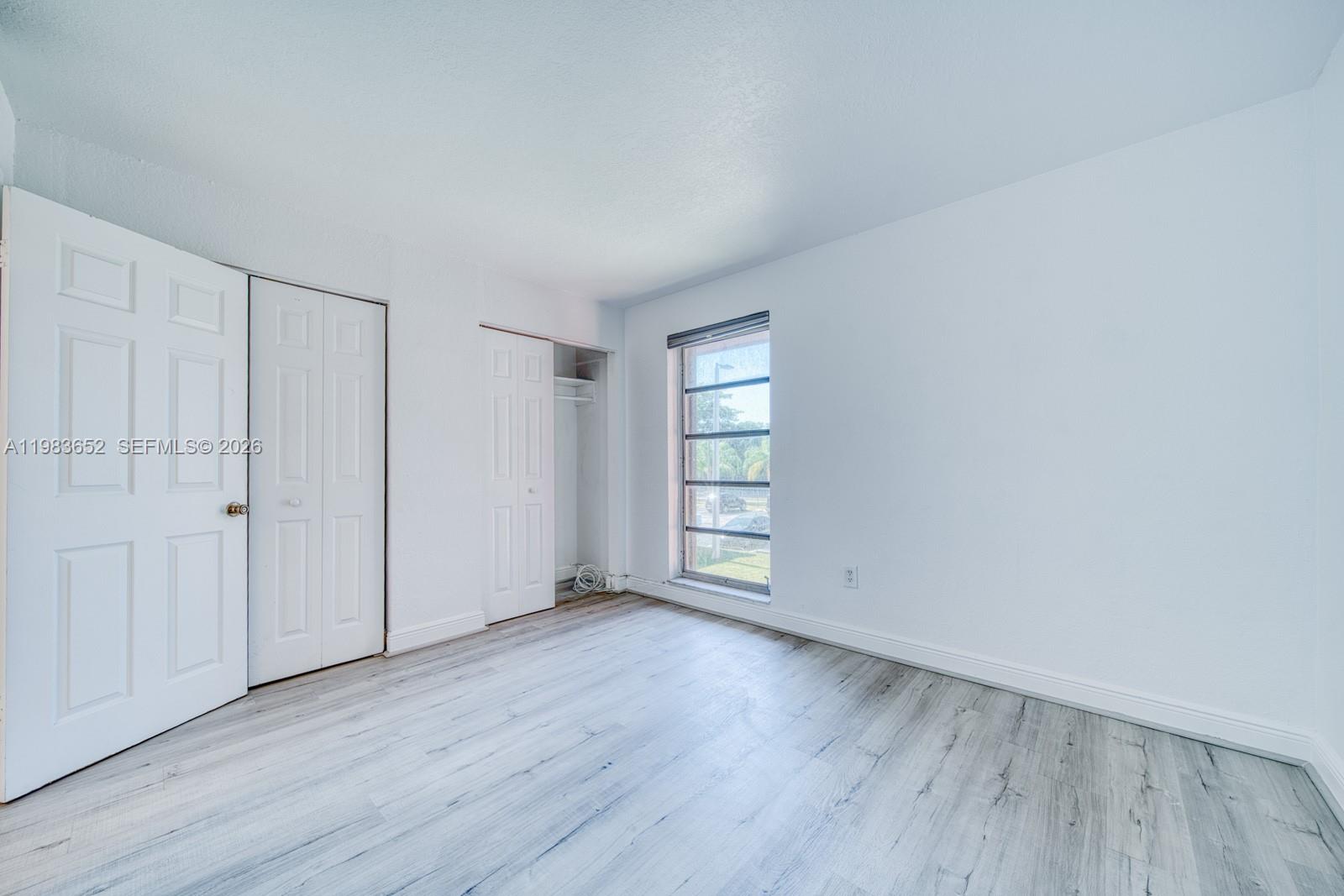 9459 Southwest 76th Street, Unit R5 Miami, FL 33173 - Photo 19 of 33 a view of an empty room with wooden floor and a window