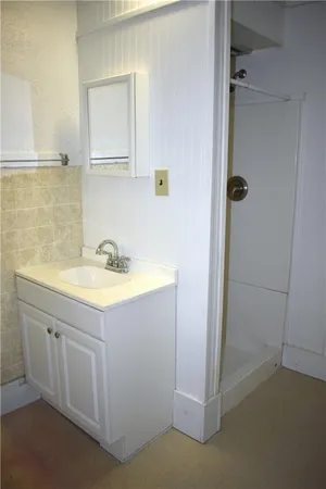 a bathroom with a granite countertop sink a mirror and a shower