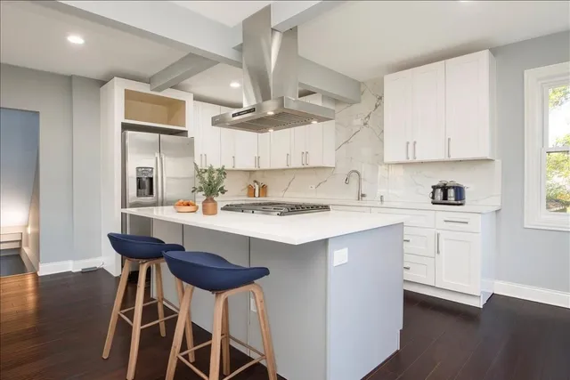 a kitchen with stainless steel appliances kitchen island a table chairs sink and cabinets