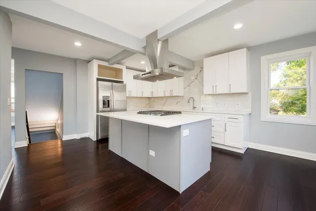a kitchen with stainless steel appliances cabinets a wooden floor and a window