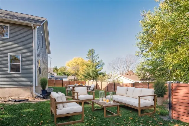a view of a backyard with couches and a fire pit and a large tree