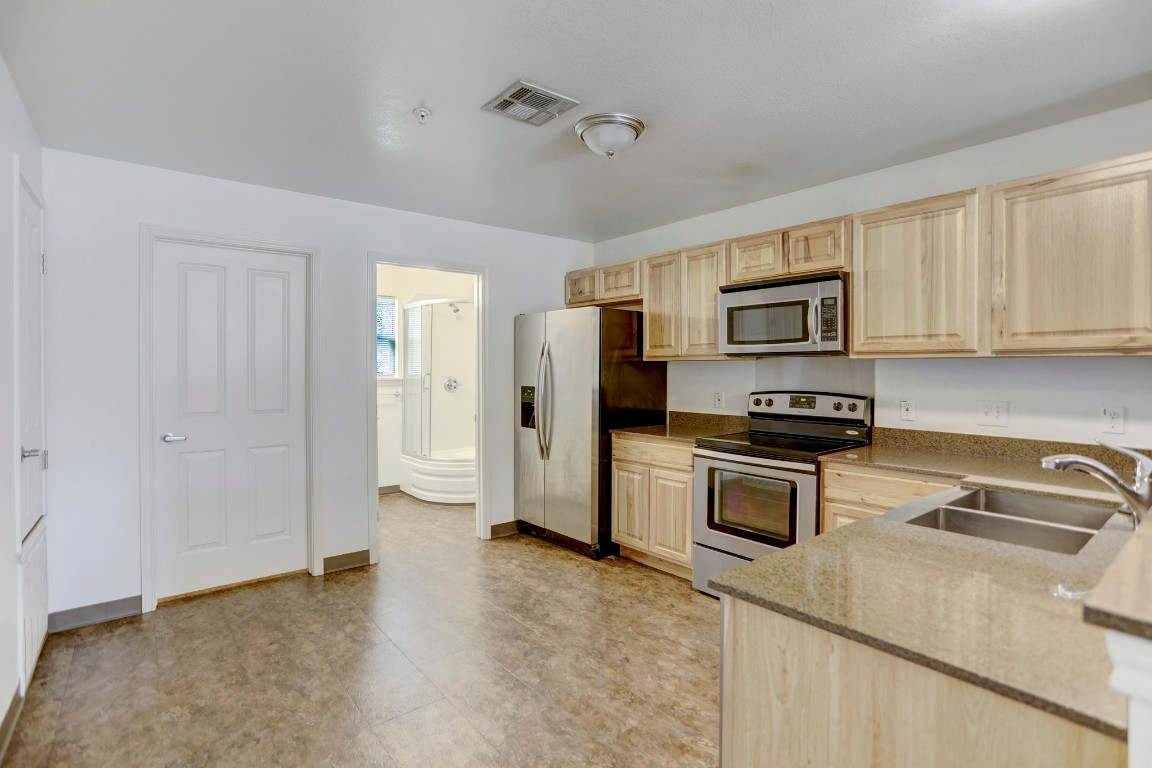 706 West 6th Street, Unit C Taylor, TX 76574 - Photo 5 of 14 Kitchen with light brown cabinetry, appliances with stainless steel finishes, and stone counters