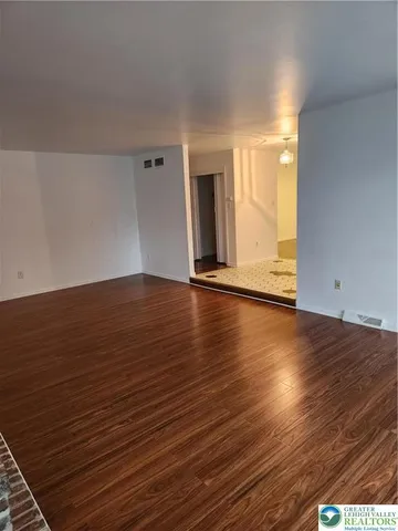 a view of an empty room with wooden floor and a fireplace