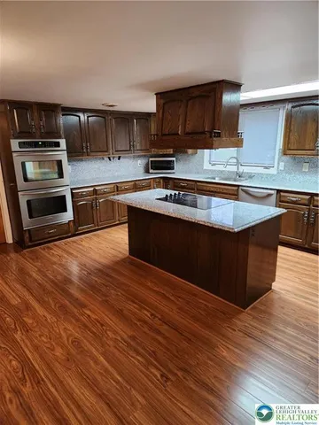 a large kitchen with wooden floors and stainless steel appliances