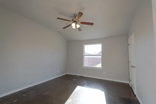 an empty room with a window and ceiling fan