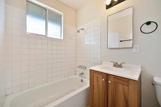 a bathroom with a bathtub sink vanity and mirror