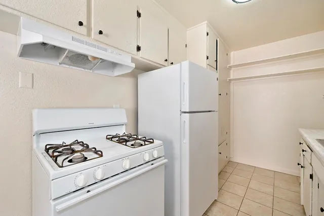 a white refrigerator freezer and a stove sitting inside of a kitchen