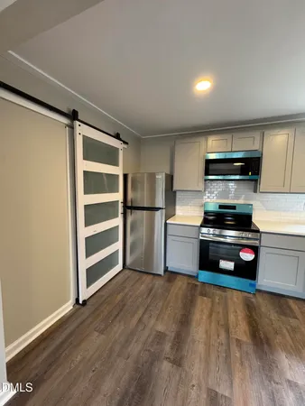 a kitchen with granite countertop a refrigerator and a stove top oven