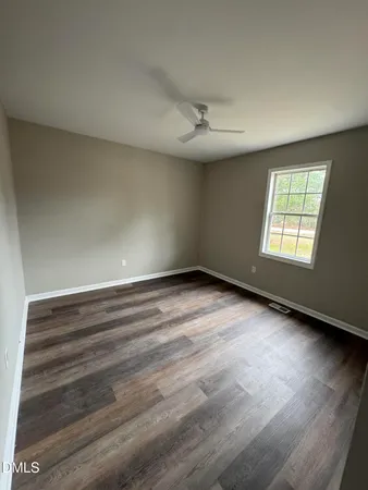 an empty room with wooden floor ceiling fan and windows