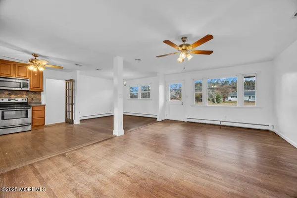 a view of a kitchen with furniture a ceiling fan and wooden floor