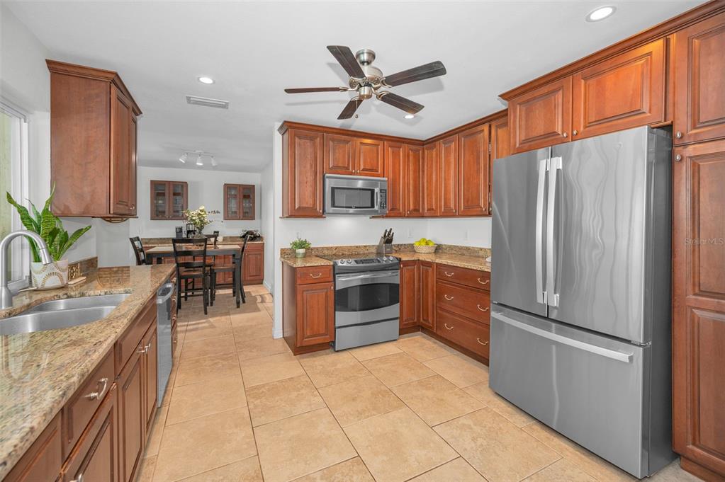2949 Glenpark Road Palm Harbor, FL 34683 - Photo 17 of 60 a kitchen with stainless steel appliances granite countertop a refrigerator a stove a sink a dining table and chairs with wooden floor