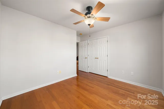 an empty room with a ceiling fan and wooden floor