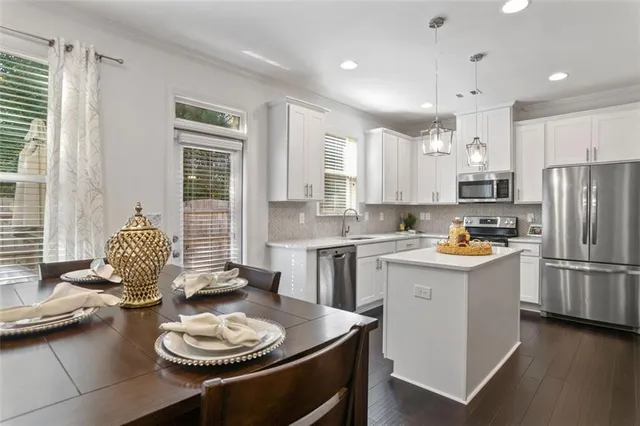 a kitchen with a refrigerator a sink dishwasher a stove and white cabinets with wooden floor