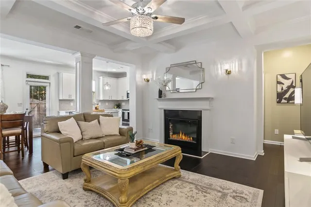 a living room with furniture a clock and a view of kitchen