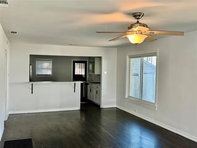a view of an empty room with a window and wooden floor
