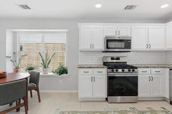 a kitchen with white cabinets a window and stainless steel appliances