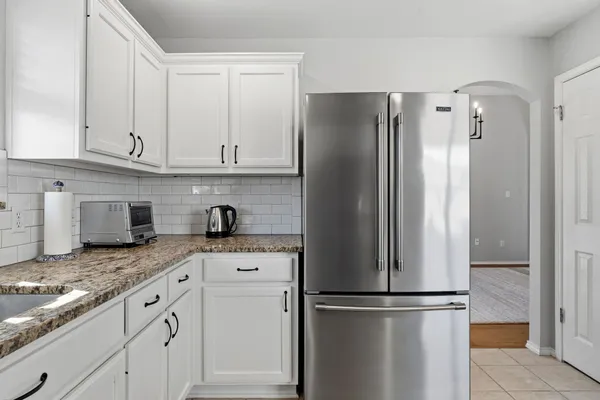 a kitchen with granite countertop a refrigerator and cabinets