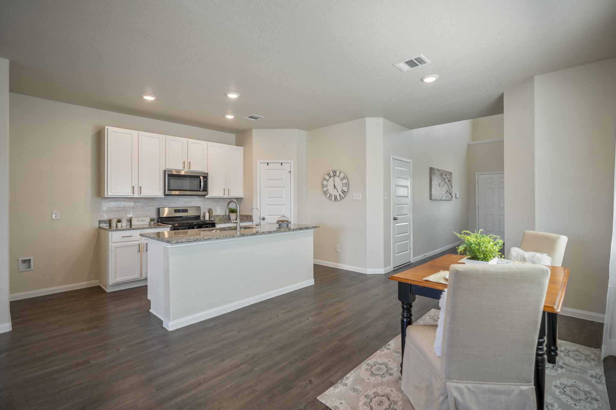 2355 Mount Locke Path Conroe, TX 77301 - Photo 5 of 47 Circling back at the dining area gives a wider look at how naturally it connects with the kitchen. The island stretches across the center for prep and casual seating, while the cabinetry, stainless appliances and updated backsplash line the far wall. The pantry is tucked beyond the kitchen to the right, keeping storage close at hand without interrupting the open flow of the space.