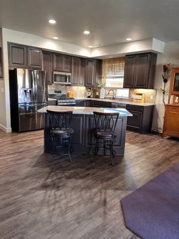 a kitchen with kitchen island granite countertop wooden cabinets a counter top space a sink and appliances