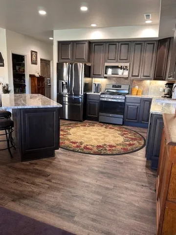 a kitchen with stainless steel appliances wooden floor and refrigerator
