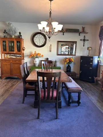 a view of a dining room and livingroom with furniture wooden floor a rug and a chandelier