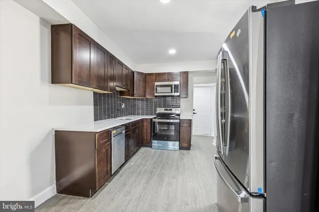 a kitchen with stainless steel appliances granite countertop a refrigerator a stove a sink and a microwave