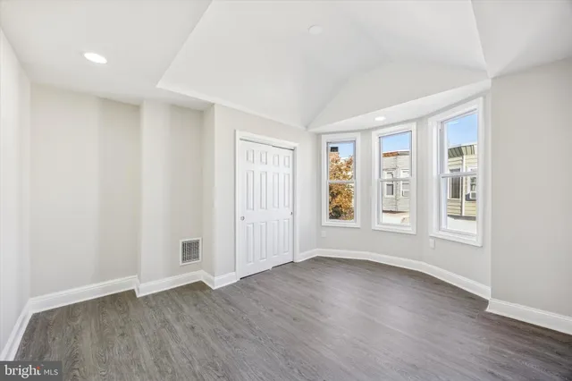 an empty room with wooden floor and windows