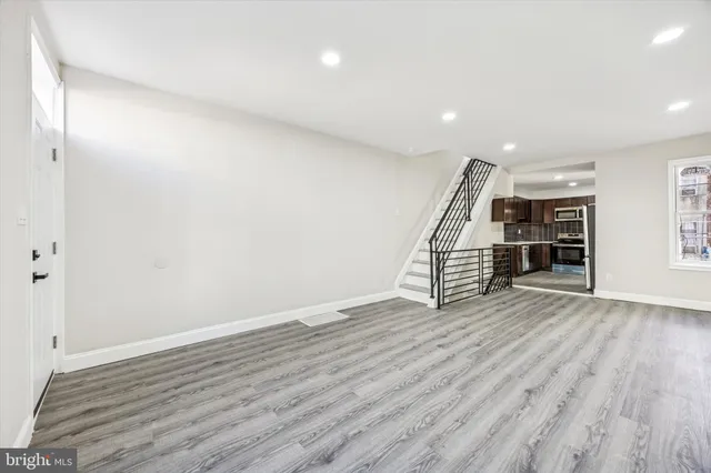 an empty room with wooden floor and way to ceiling window
