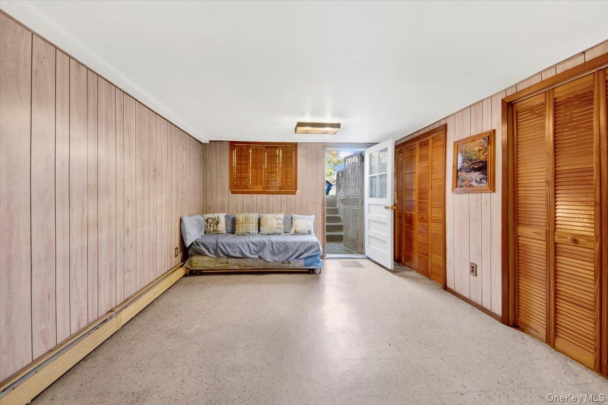 733 Rhinelander Avenue Bronx, NY 10462 - Photo 22 of 31 Bedroom featuring a baseboard radiator, tile patterned floors, two closets, and wood walls