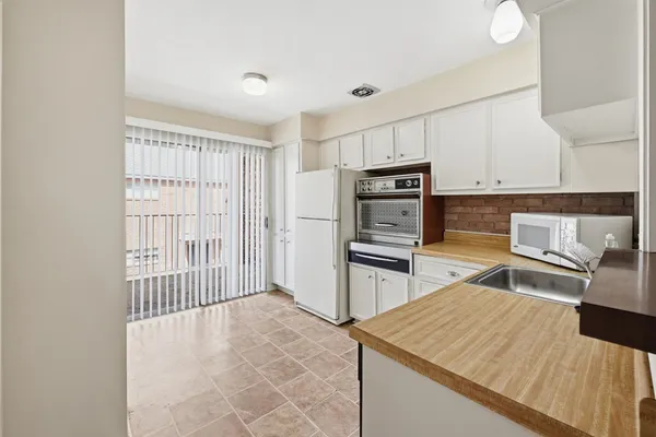 a kitchen with stainless steel appliances kitchen island granite countertop a refrigerator oven stove with white cabinets and wooden floor