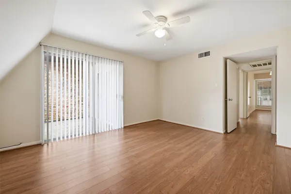 an empty room with wooden floor and ceiling fan