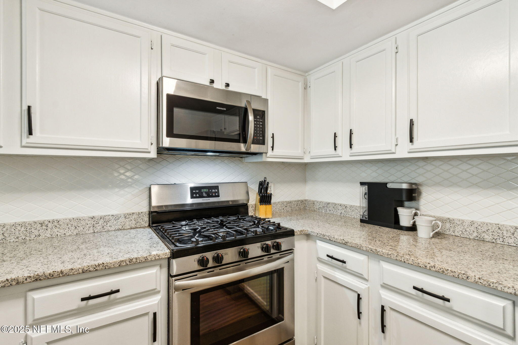 2751 West 5th Street, Unit B Fernandina Beach, FL 32034 - Photo 18 of 61 a kitchen with granite countertop white cabinets and appliances