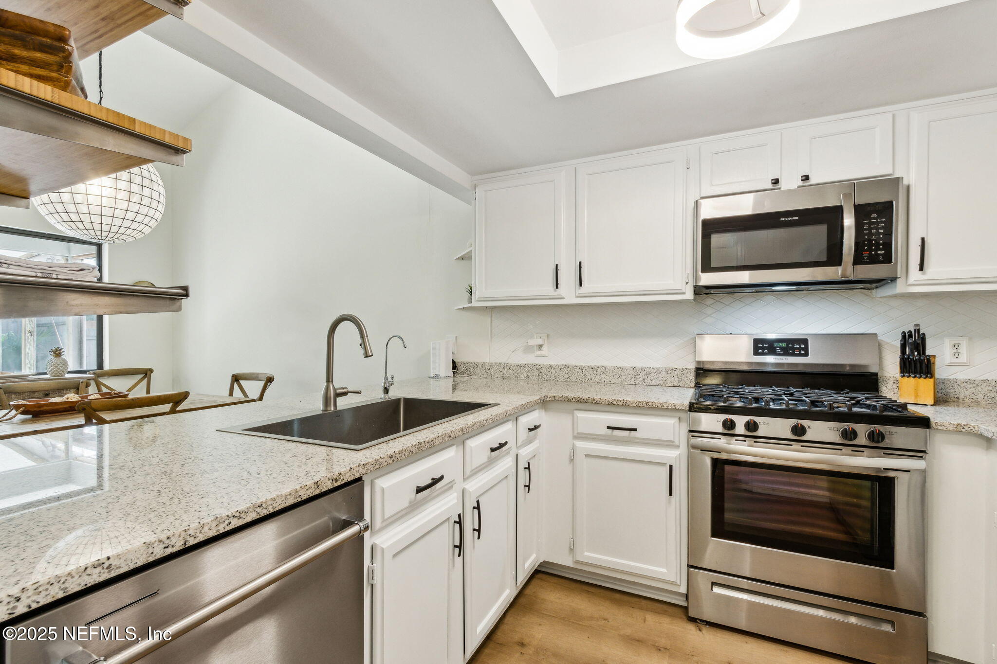 2751 West 5th Street, Unit B Fernandina Beach, FL 32034 - Photo 5 of 61 a kitchen with stainless steel appliances granite countertop a sink dishwasher a stove and a microwave oven with white cabinets