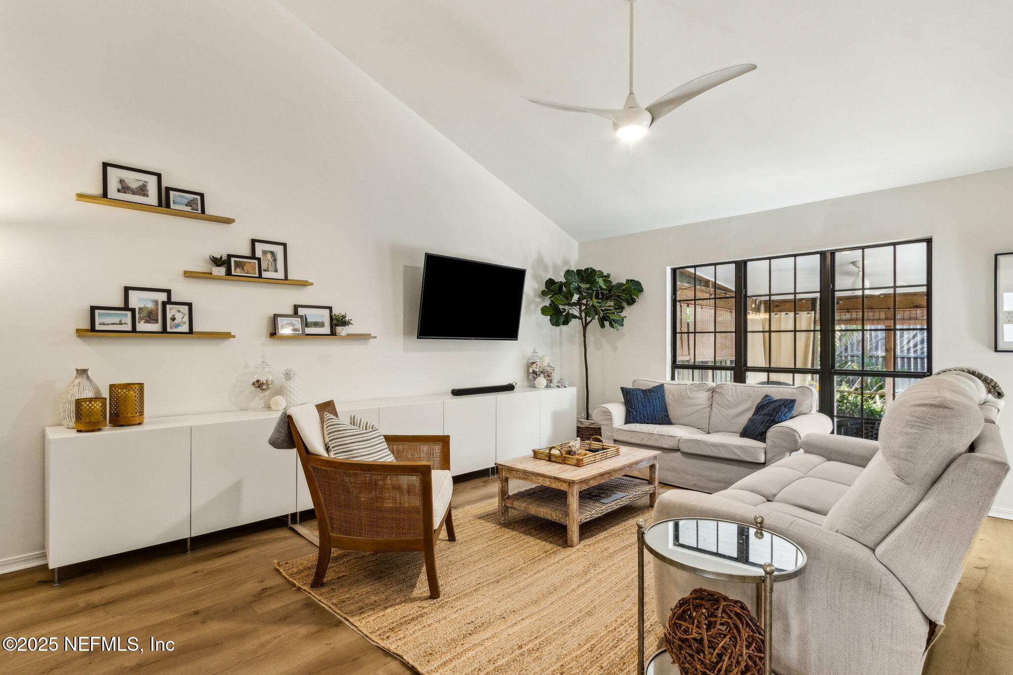 2751 West 5th Street, Unit B Fernandina Beach, FL 32034 - Photo 6 of 61 a living room with furniture a flat screen tv and a floor to ceiling window
