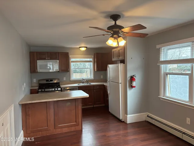 a kitchen with stainless steel appliances granite countertop a refrigerator a sink dishwasher a dining table and chairs with wooden floor