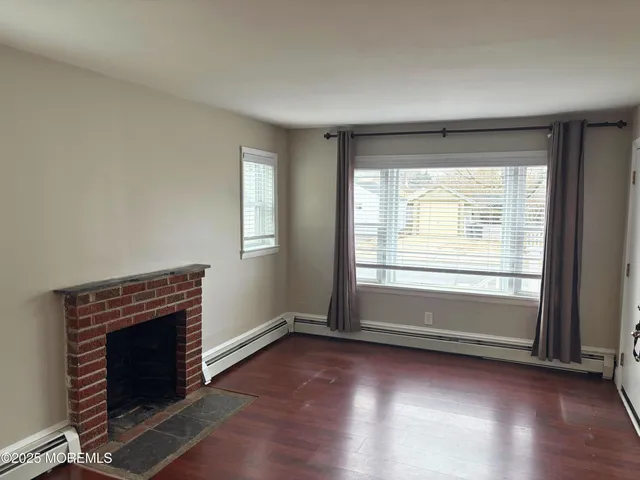 an empty room with wooden floor fireplace and windows