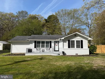 a front view of house with yard and trees in the background